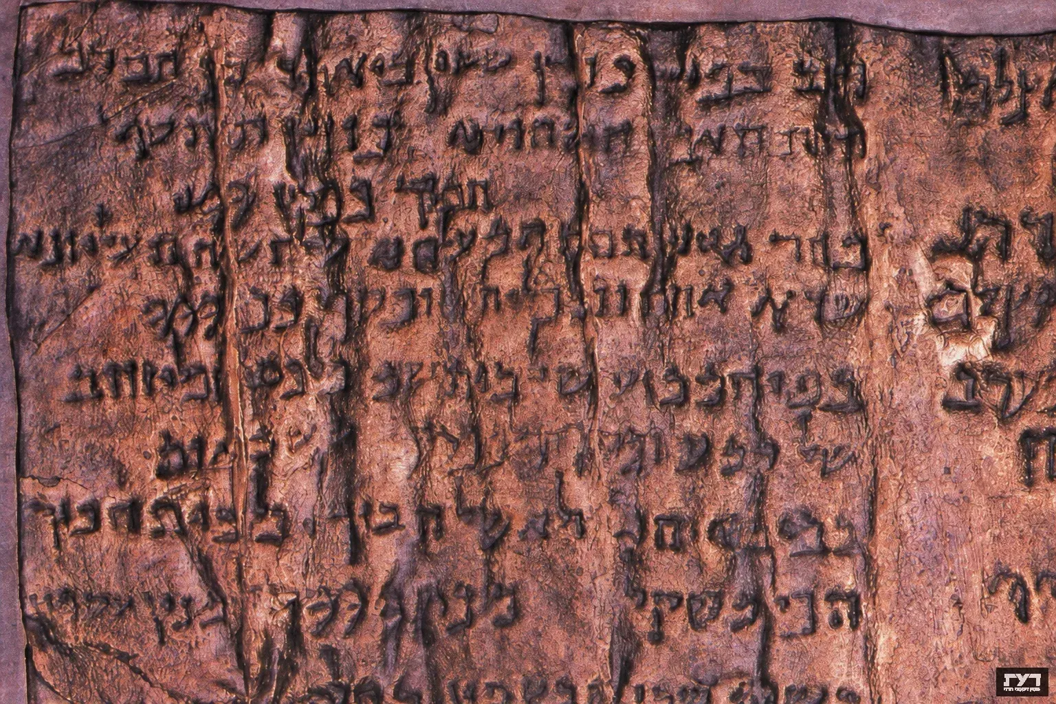 תקריב על כתב עברי עתיק חרוט על קלף בגוני חום וסגול